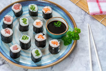 A selection of sushi rolls with salmon, tuna, cucumber and soy sauce dip.