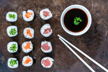 A selection of sushi rolls with salmon, tuna, cucumber and soy sauce dip - overhead view
