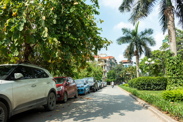 Parallel cars parking on street with green trees