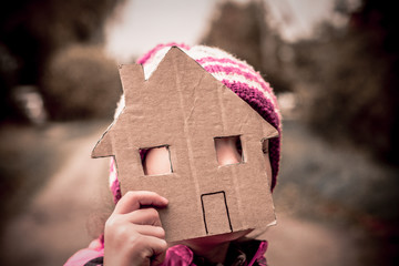 The girl is five years old. She is holding a house cut out of cardboard.