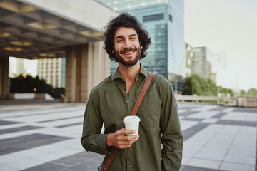 Portrait of handsome young businessman holding coffee cup standing outdoor