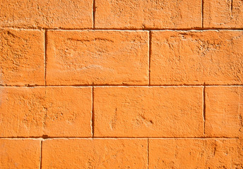 Full frame background of brightly colored orange block wall with sunny texture copy space