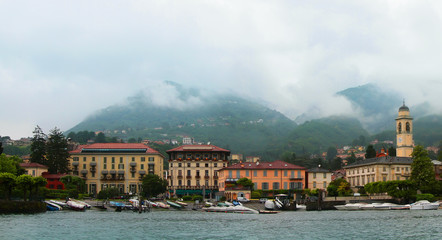 Fototapeta na wymiar Panoramic view of Como lake with villages and mountains shrouded in clouds. Cernobbio. Italy.
