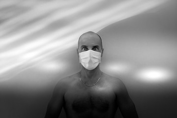 Scary vision of a lonely man wearing a protective mask on his face, scary concept of respiratory protection, man  with a disturbing look, quarantined patient