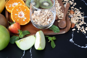 Healthy breakfast cornflakes and fruits include oranges, bananas, kiwi and strawberries  on a black background. It's a copy space.
