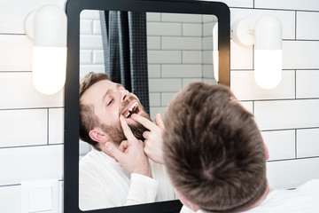 Man looks in the mirror, he opened mouth and examines the absence of a tooth that the dentist...