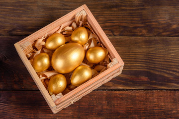 Easter eggs in gift wooden box on dark wooden background. Preparation for the holiday