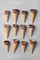 Ice cream cones variety with chocolate sprinkles flat lay on a grey background viewed from above. Top view