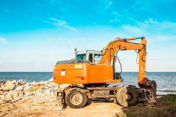 Obraz premium Scraper picking up debris from a storm-damaged beach house