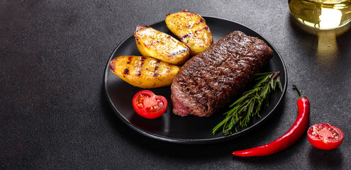 Ribeye steak with potatoes, onions and cherry tomatoes. Juicy steak with flavored butter