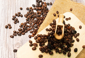 The coffee beans are placed on the wooden floor and the sack has a wooden spoon to place on the coffee beans. Relaxation concept. It's a copy space.