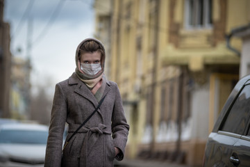 Obraz premium Young attractive woman in protective medical mask stands near a car. Protection against viruses - influenza, coronavirus and smog