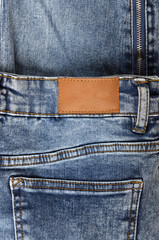 Blue jeans with zipper close-up.Jeans label.Leather label of a blue jeans.Brown leather empty copy space label texture. Back side of blue denim jeans trousers background.