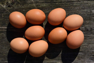 Fresh brown chicken eggs lie on a weathered wooden table and are photographed from above