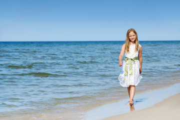 Fototapeta na wymiar Beautiful girl in a dress walking on the beach
