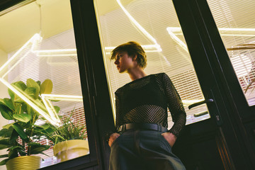 Pretty young girl tomboy teen model trendy dark clothing stand arms in pockets pose over big...