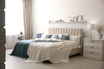 Comfortable bed with pillows in room. Stylish interior design