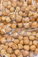 Packing from a transparent bag with peeled hazelnuts. Vertical.
