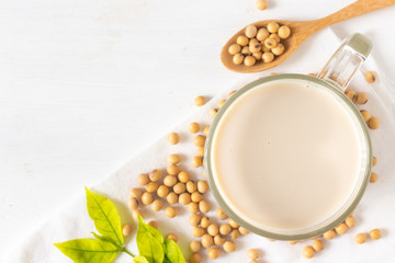 Top view of Soy or soya milk in a glass with soybeans in a wooden bowl background