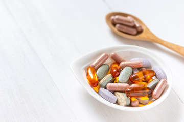 Variety of vitamin pills on white wooden background, supplemental and healthcare product