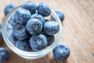 Blueberries in a glass bowl on wooden table and texture, fresh fruit with water droplet