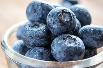 Blueberries in a glass bowl on wooden table and texture, fresh fruit with water droplet