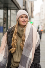 Beautiful young woman in winter autumn outfit walking in the city street