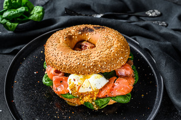 Smoked salmon bagel toasts with soft cheese, spinach and egg. Black background. Top view - obrazy, fototapety, plakaty