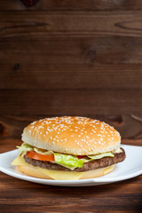 Burger on a plate and wooden background. Copy space.