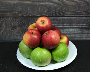 red and green apples in drops of water on a dish