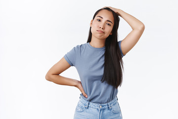 Puzzled, doubting young brunette girl cant decide what wear on party, sighing and scratch head, look indecisive, put hand on hip, have problem with making choice, standing questioned white background