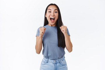 Relieved, happy emotional good-looking asian woman feeling sweet success, scream from happiness and...