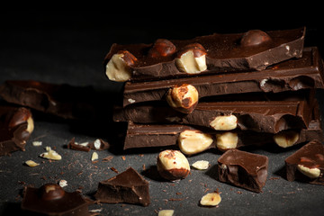 Pieces of chocolate with a nuts tied with a white and red   lying on a dark texture table.