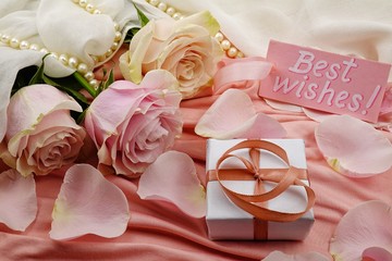 Bouquet of pale pink roses and Best Wishes card lay on the white background