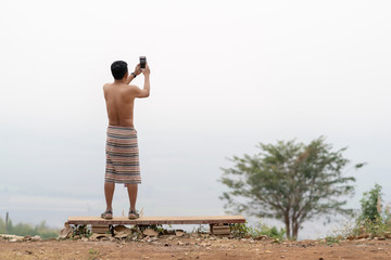 man with naked torso in loincloth is standing on the edge of a cliff and looks at the fog.