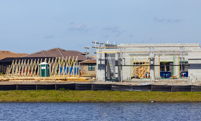 Obraz premium A new home next to a small lake is shown under construction. Only the foundation and cinder block walls are in place, there is no roof yet.