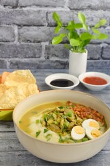 Bubur Ayam, Indonesian rice congee with shredded chicken, scallion, celery, fried soybean, boiled quail egg, yellow chicken broth and kerupuk