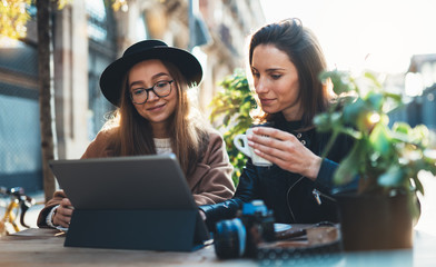 Friends businesswoman using digital tablet. Girls sitting in cafe. Busines communication. Internet laptop technology working process project