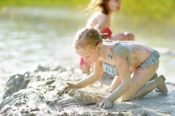 Two young sisters taking healing mud baths on lake Gela near Vilnius, Lithuania. Children having...