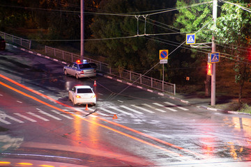 At the crossroads at night, the driver violated and knock down a pedestrian. The police draw up a road traffic accident. Police inspector car with emergency flashing lights.