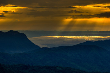 abstract background blur view of the sun shining through the clouds,surrounded by large mountains and various species of trees