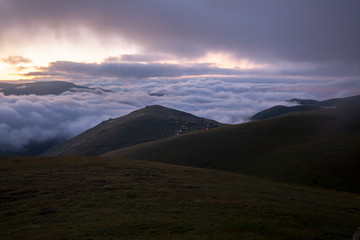 grassy mountains landscape with fog sky and sunset