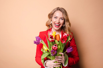 Portrait of beautiful fashion woman posing with colorful tulips having positive emotion medium shot. Smiling luxury young female holding bouquet of fragrance flowers isolated at studio background