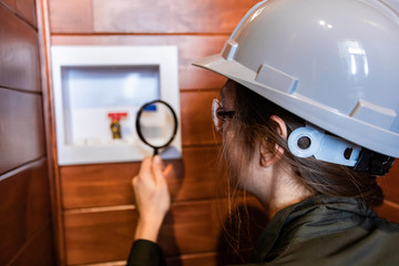 selective focus on inspector woman's hand holding a magnifying glass to check hot and cold water entry for a washing machine. inspecting a modern home
