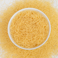 Raw vermicelli pasta in a bowl isolated on white background.