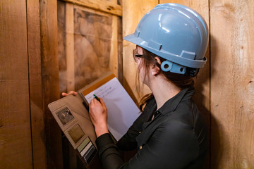 Indoor air quality inspector woman rear view as she looks closely for molds or fungi problems on...