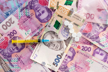 Syringe, pills in zip lock plastic bag and lot ukrainian money. Sale of drugs, сocaine, heroin or ecstasy. Illegal business. Healthcare and medical concept.