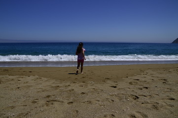 ni&ntilde;a sola corriendo a orillas del mar