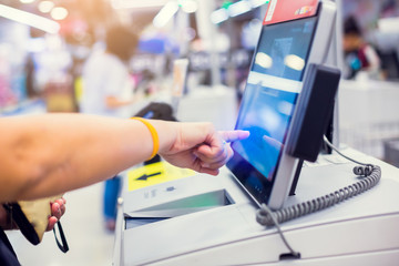 The woman customer is pressing the screen of the automatic payment machine. Self service machine in...