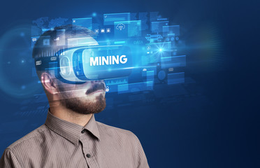 Businessman looking through Virtual Reality glasses with MINING inscription, innovative security concept